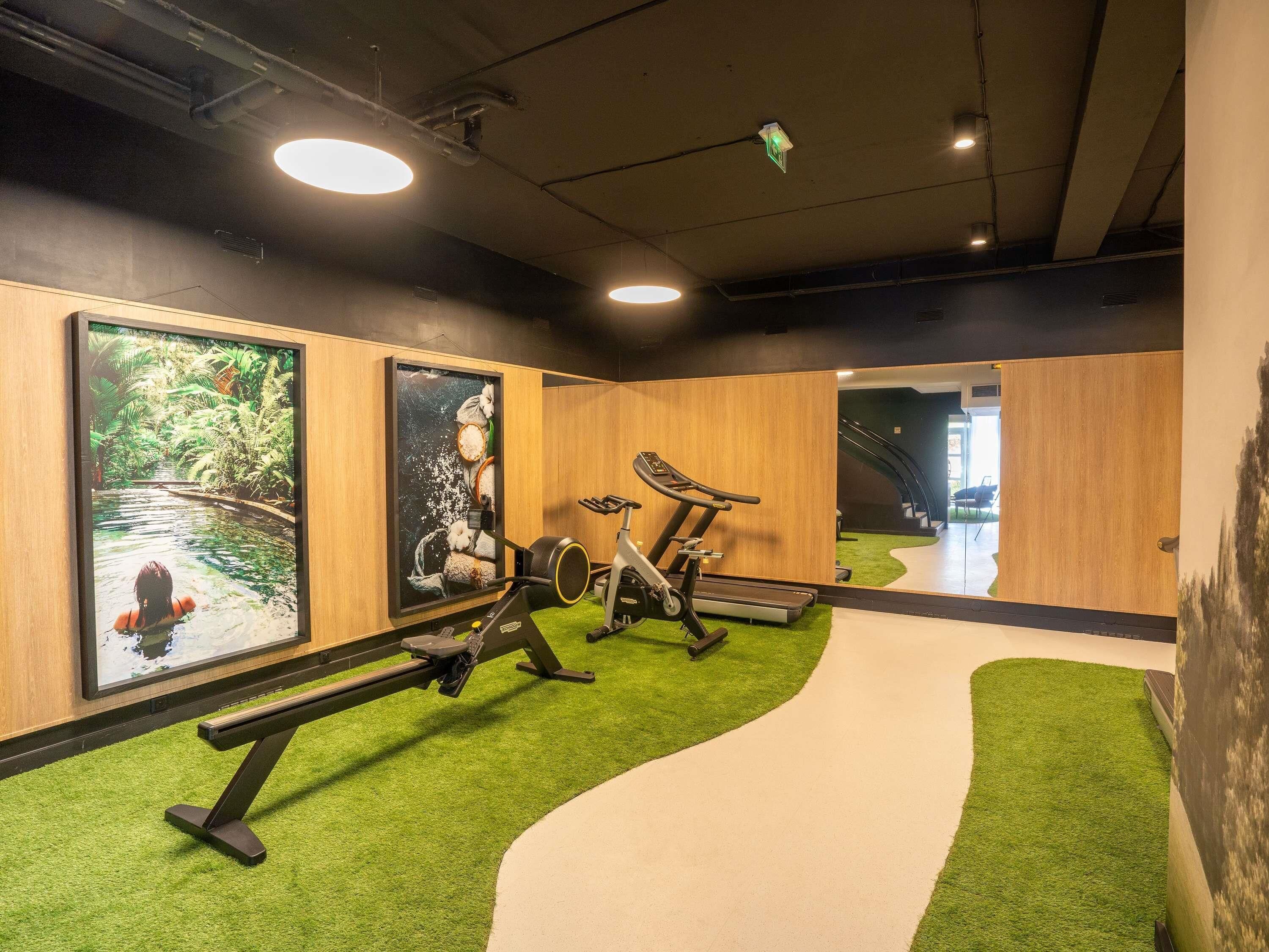 A gym with exercise equipment, a treadmill, and a wall-mounted television.
