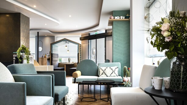 Una moderna hall d'albergo con aree relax, una reception e un'ampia finestra con vista.