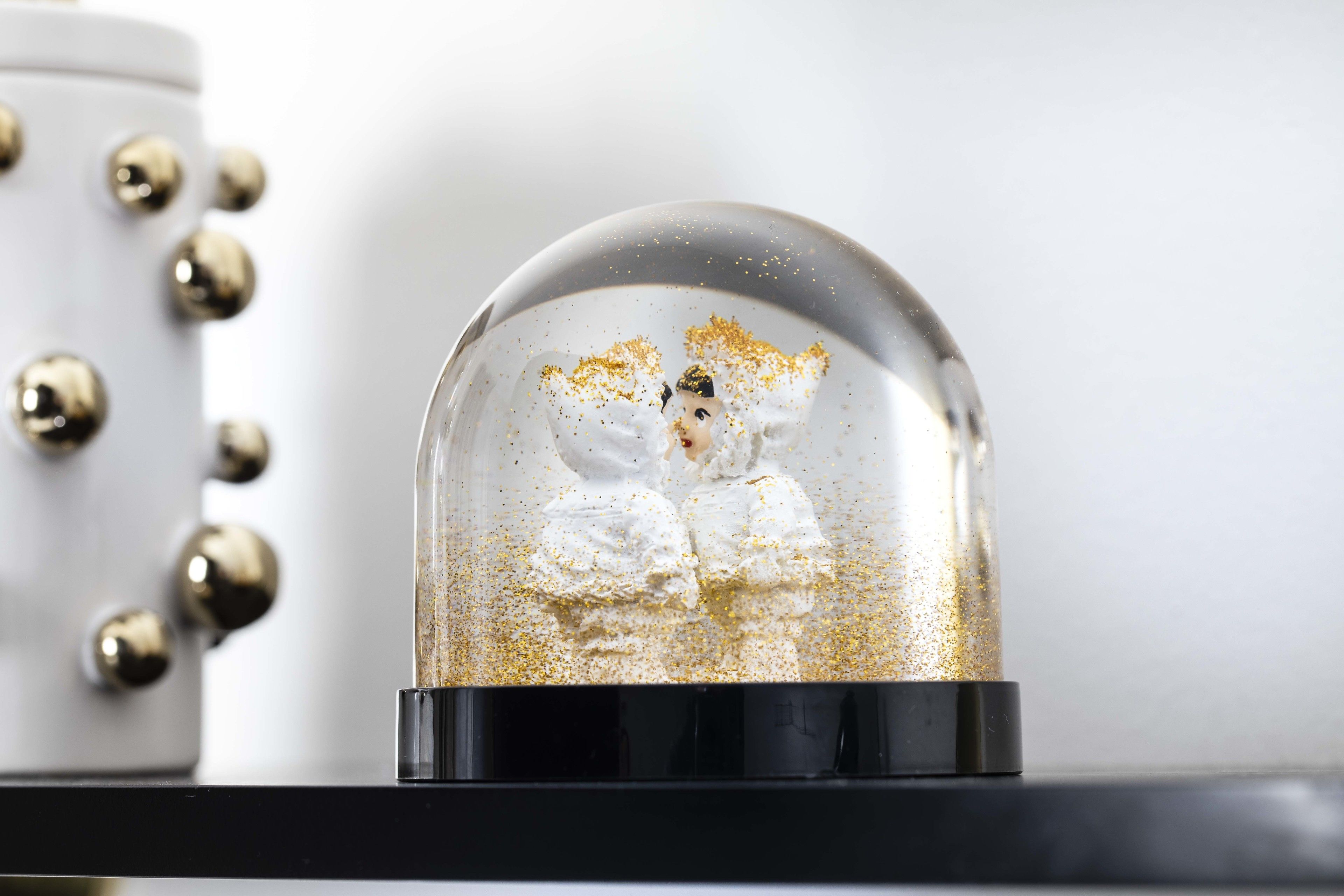 A snow globe with a figure inside, placed on a black surface.