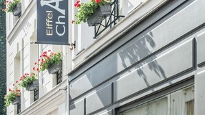 A building with multiple balconies adorned with red flowers and a sign reading "Eiffel Saint Charles". - Hôtel Eiffel Saint Charles (Paris)