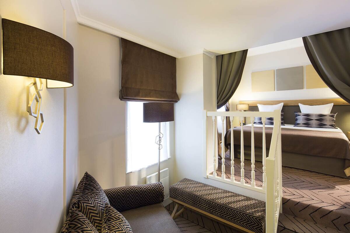 A bedroom with a bed, a window with curtains, a bedside table, and a chair.