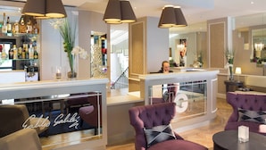Een hotel lobby met een bar, zitplaatsen met kussentjes en een glazen displaykast.