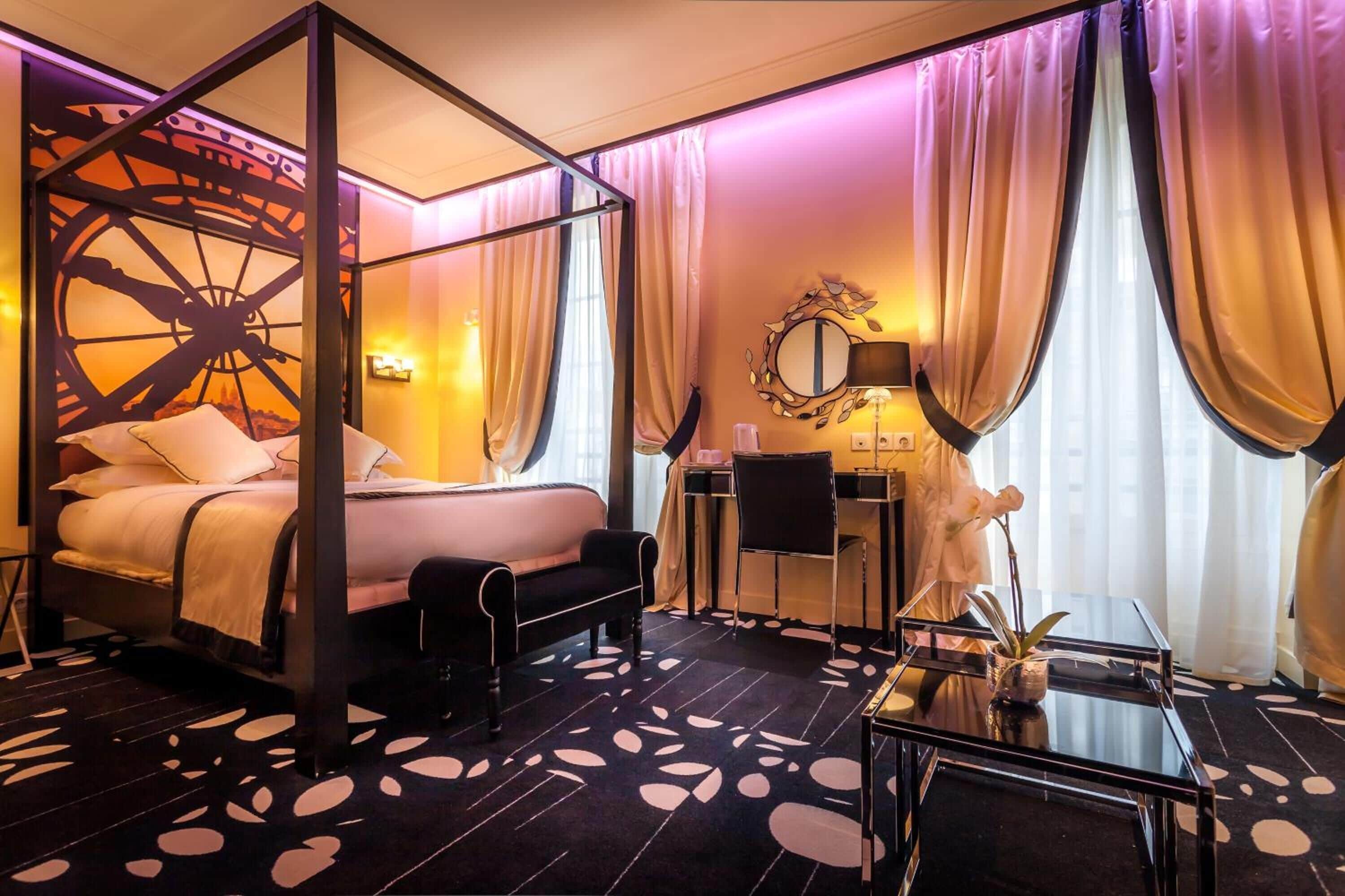 A four-poster bed with a canopy, a desk with a chair, and a mirror on the wall.