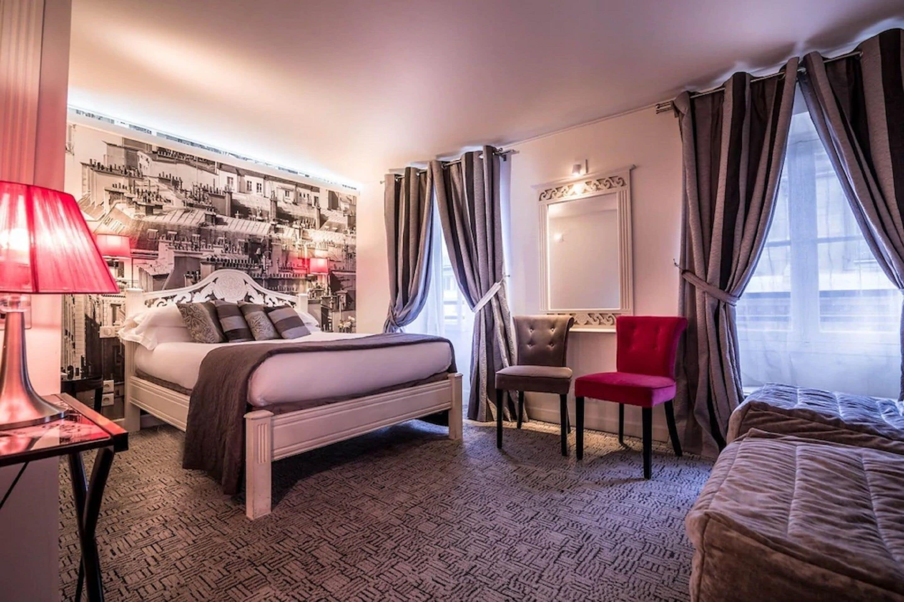 Een hotelkamer met een bed, een bureau, een stoel en een groot raam met gordijnen.