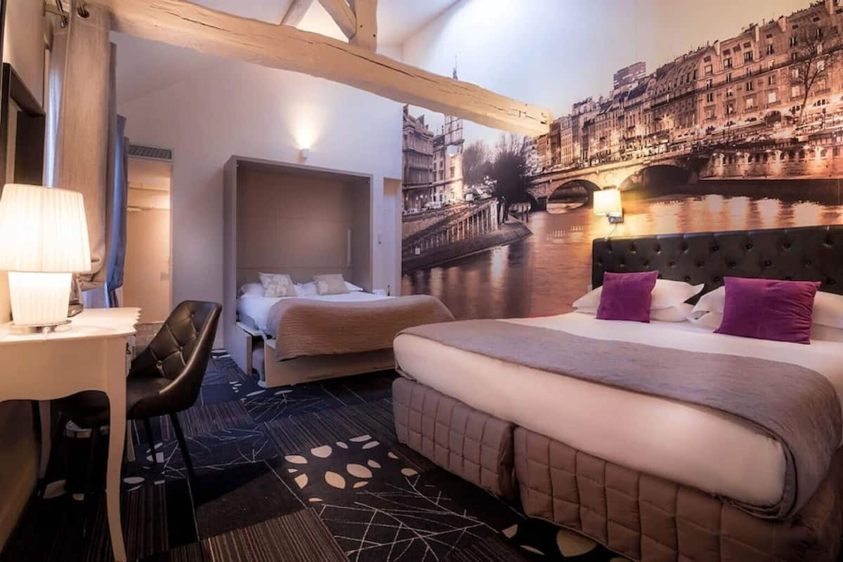 Habitación de hotel con cama, escritorio y silla. Amplia ventana con vista a la ciudad.