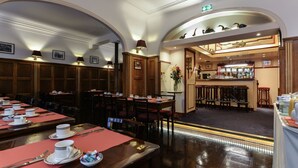 Een restaurant met verschillende eettafels, stoelen en een bar.