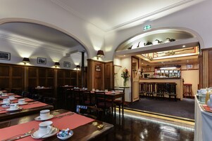 Un restaurante con varias mesas, sillas y una zona de bar.