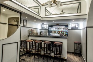 Una zona de bar con taburetes y mostrador con botellas.