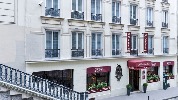 Een hotelgevel met meerdere ramen, een trap en een rode luifel met de naam van het hotel.