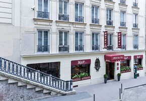 Fachada de hotel con varias ventanas, una escalera y un toldo rojo con el nombre del hotel.