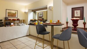 A modern kitchen with a dining area, featuring a buffet setup, bar stools, and a decorative vase. - Résidence du Pré (Paris)