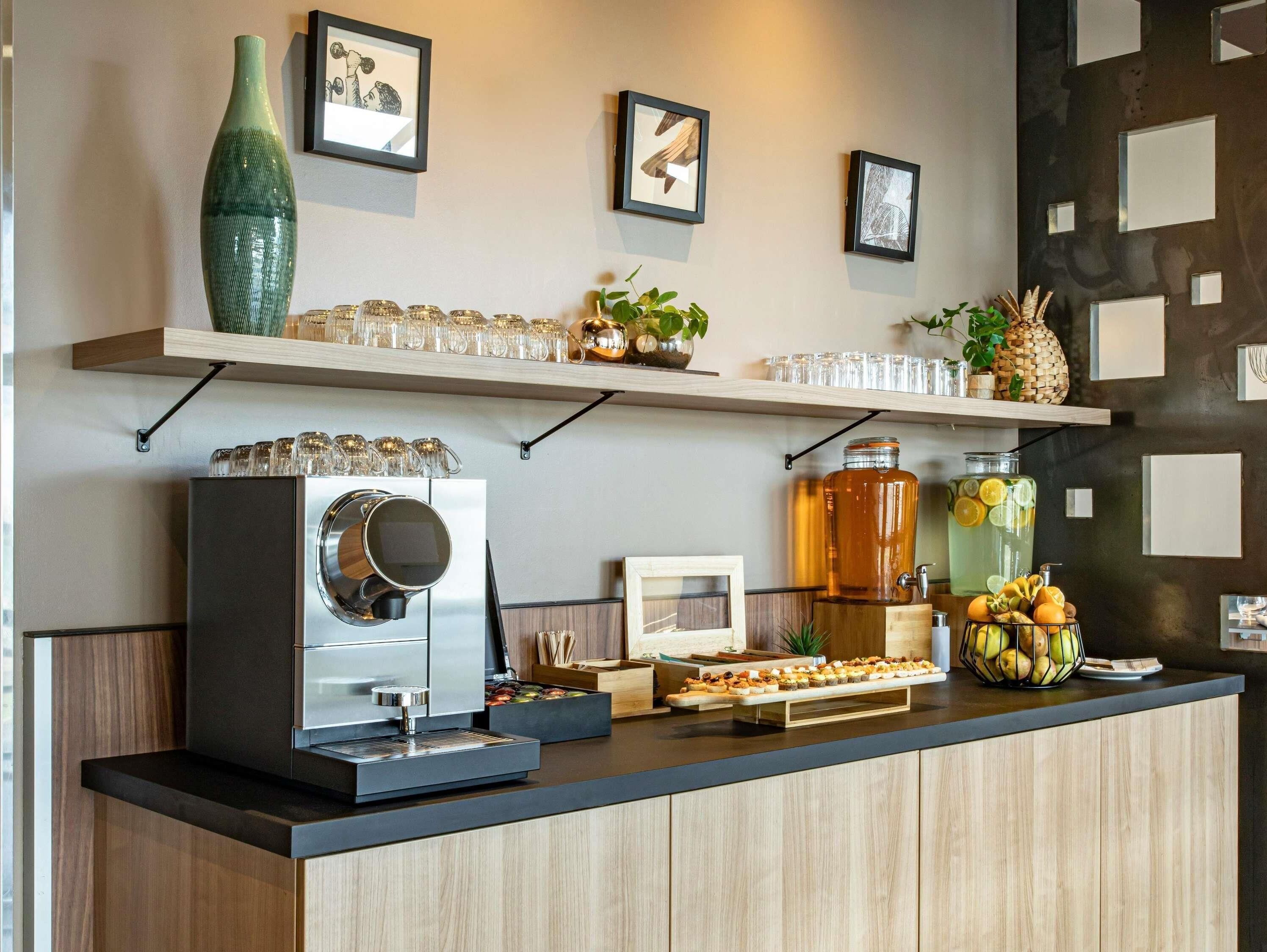 A modern kitchen with a coffee machine, a fruit display, and decorative items on shelves.