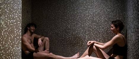 A small, tiled room with a bench and a person sitting on it.