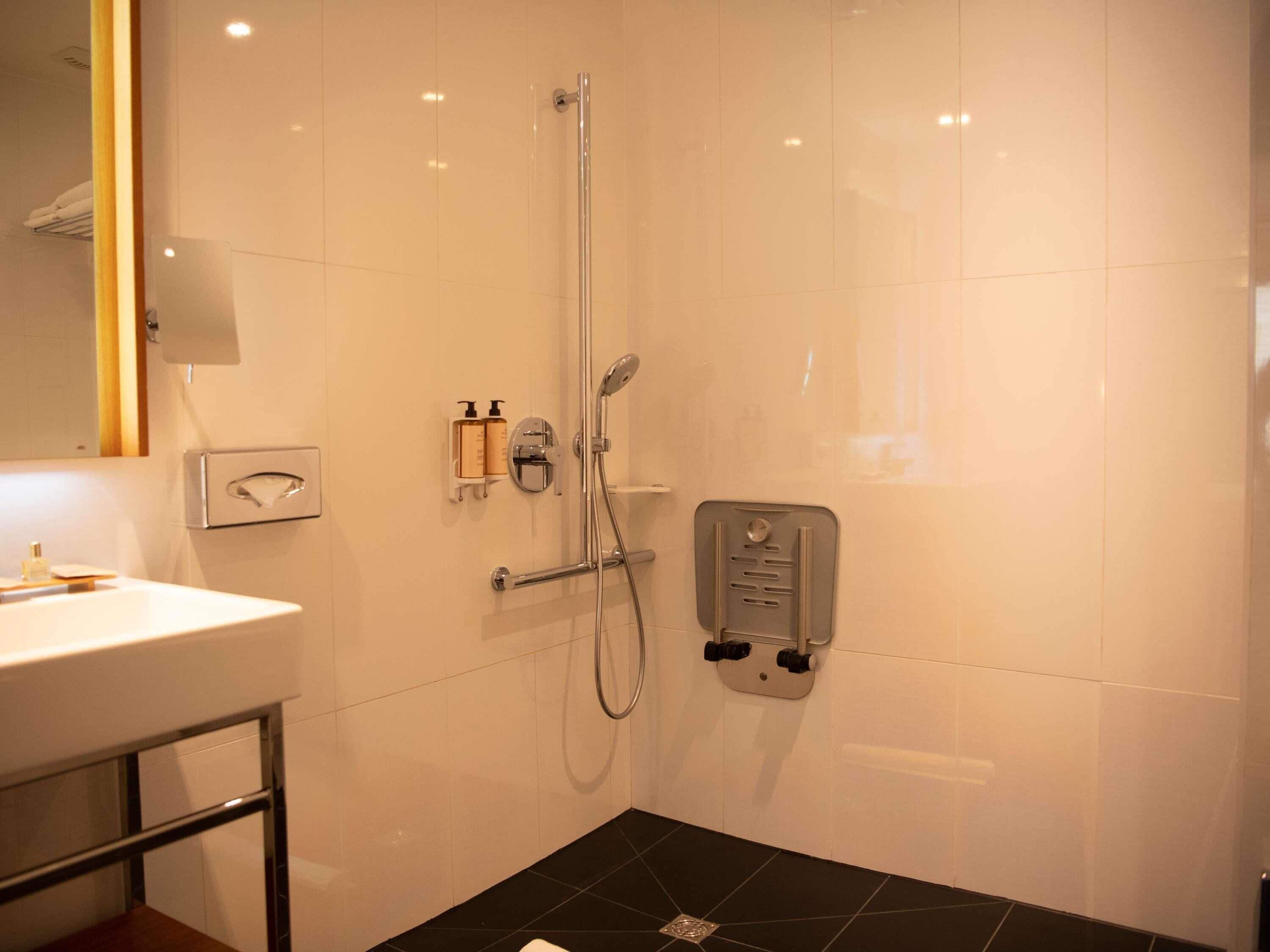 Une salle de bain moderne avec un lavabo blanc, une douche en verre et un sol carrelé de noir.
