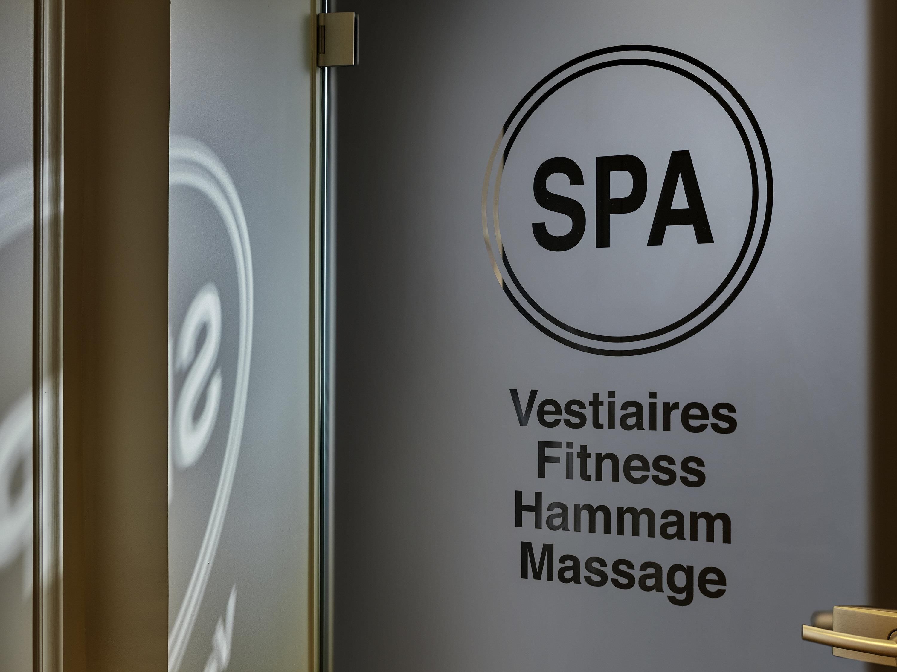 A wall with a spa sign indicating services like Vestaires, Fitness, Hammam, and Massage.