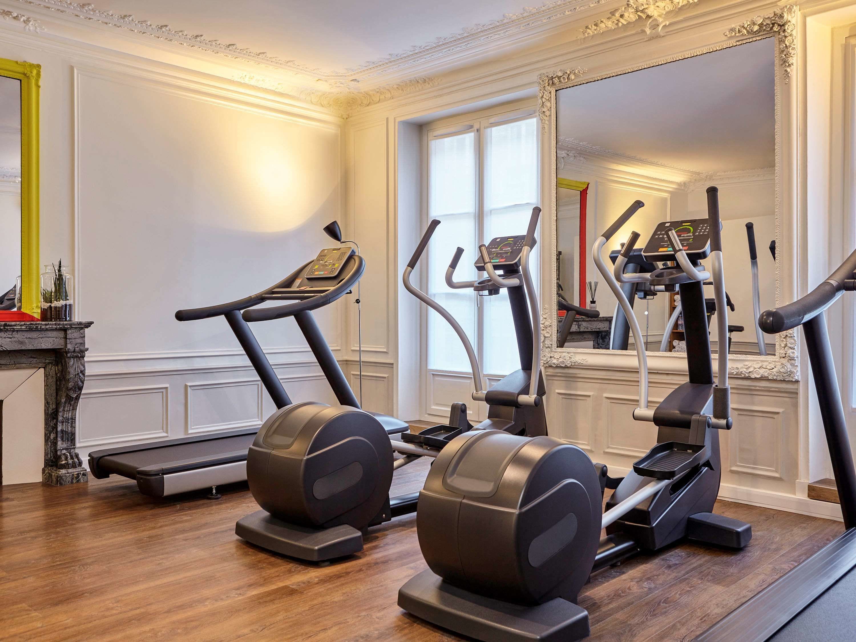 Un gimnasio en casa con cintas de correr, elípticas y una bicicleta estática.