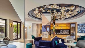 A modern interior with a central seating area, a bar, and a view of the outdoors. - Mercure Paris Opéra Garnier (Paris)