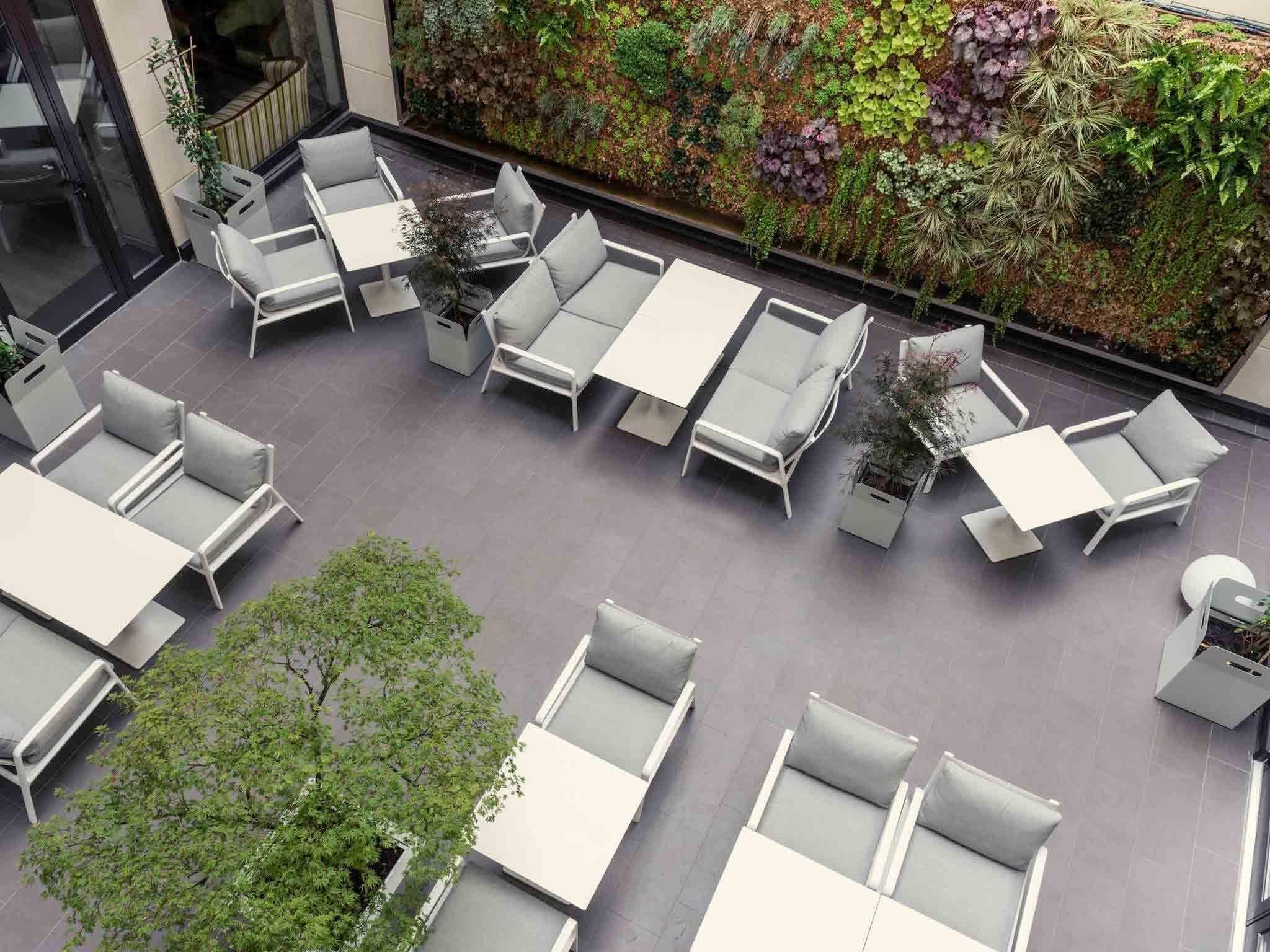 An outdoor seating area with white furniture and a vertical garden wall.