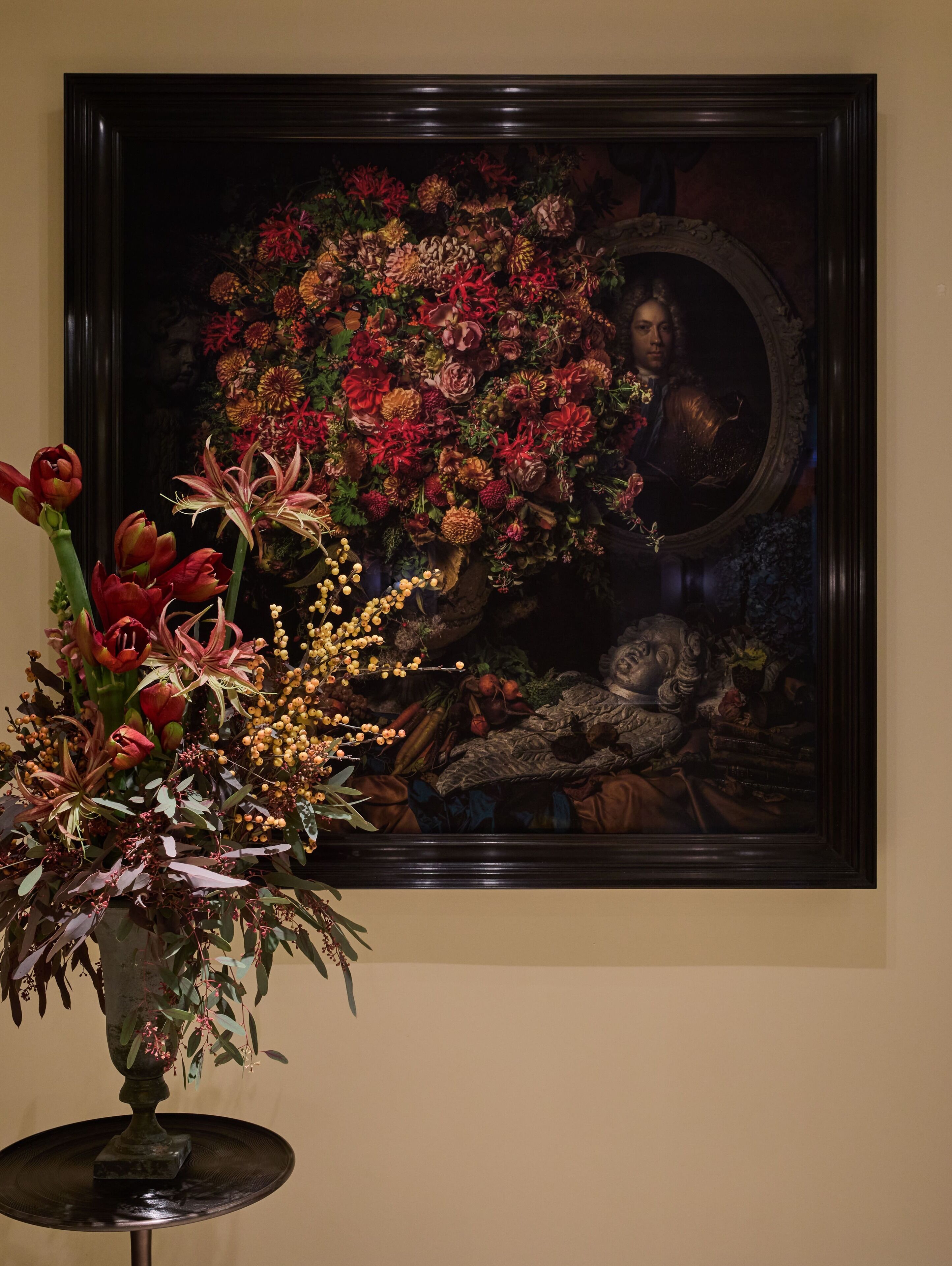 A framed painting with a floral arrangement in front of it.