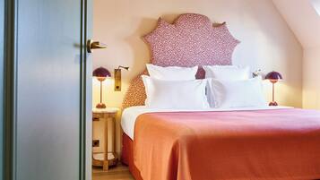 Una cama bien hecha con una colcha roja y almohadas blancas, un cabecero estampado de leopardo y dos lámparas de noche.