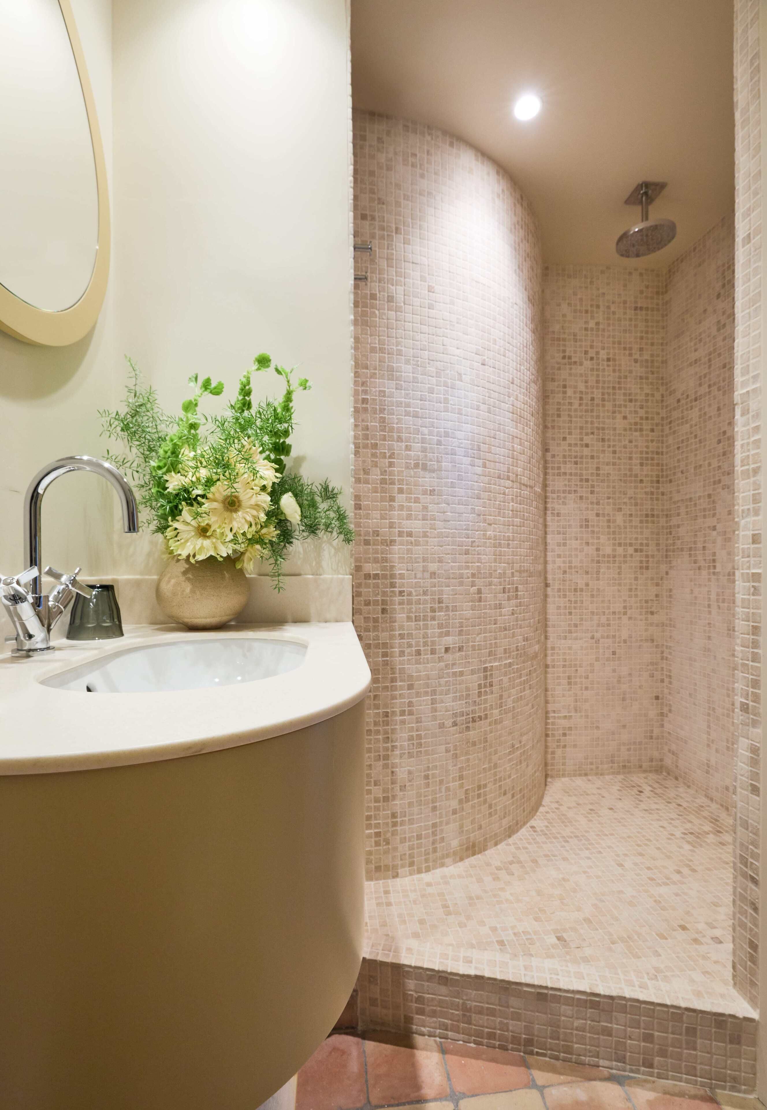 Un baño con una bañera independiente, un lavabo con espejo y una zona de ducha con paredes de mosaico.