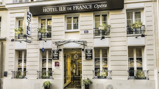 A hotel facade with balconies, a French flag, and a sign reading "HOTEL ILE DE FRANCE Opéra". - Hotel Ile de France Opéra (Paris)