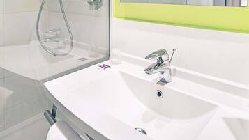 Ein modernes Badezimmer mit einem weißen Waschbecken, einem Chromarmaturen und einer Glasdusche.