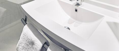 A bathroom with a white sink, a towel rack, and a glass shower enclosure.