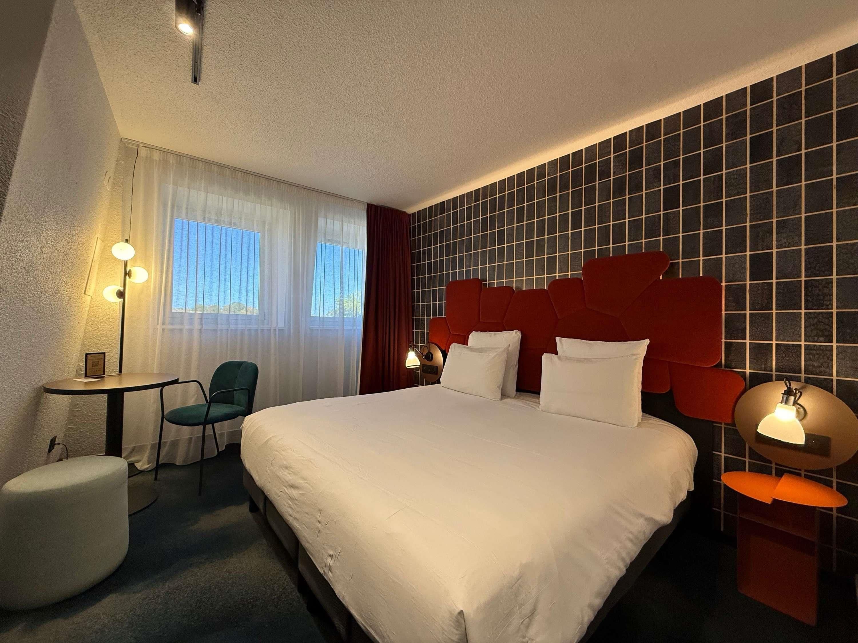 Hotellihuone, jossa on suuri sänky, työpöytä, tuoli ja pieni pöytä.