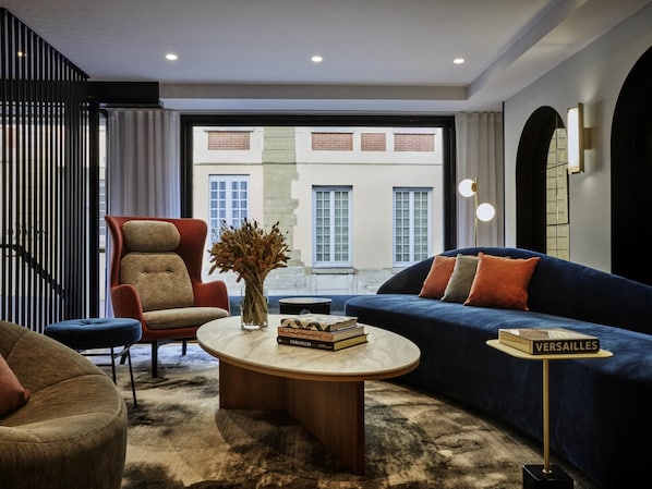 Una sala de estar moderna con sofá, sillón, mesa de centro y estantería.