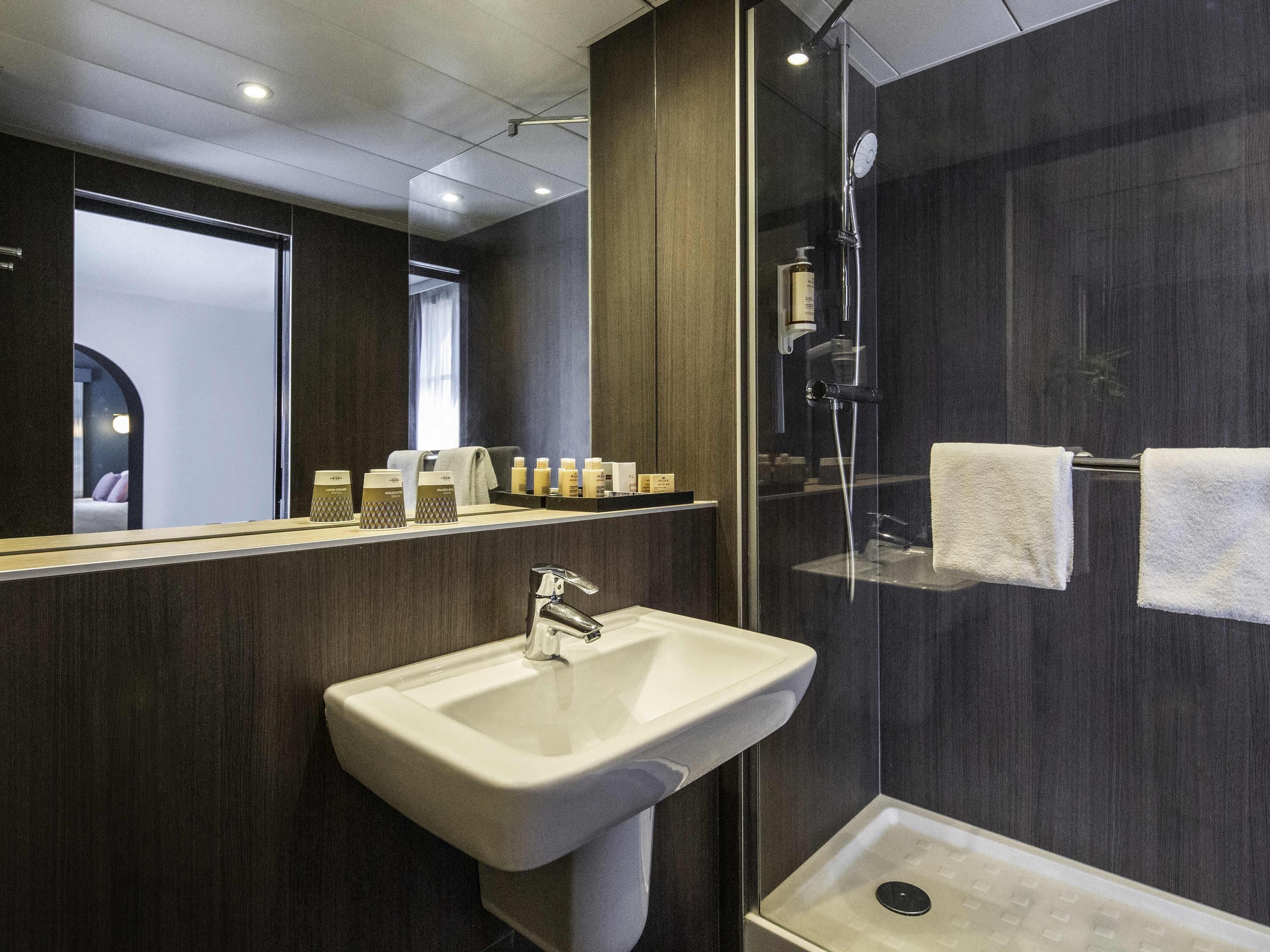 Une salle de bain moderne avec un lavabo, un miroir et une douche.