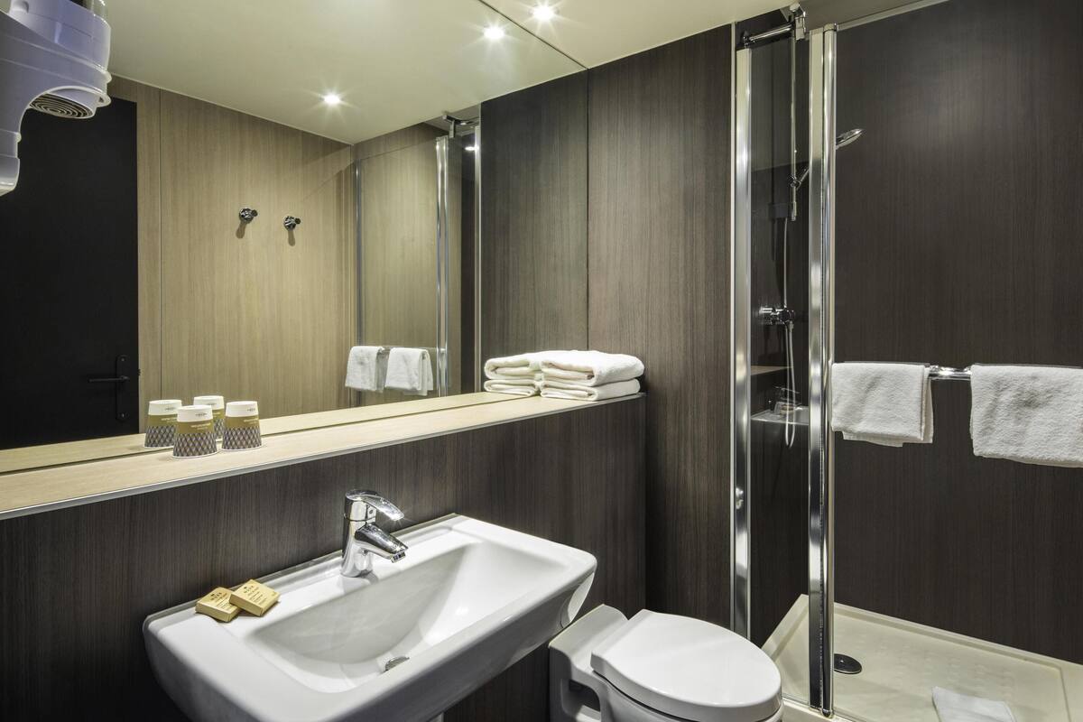 A modern bathroom with a sink, toilet, and glass shower enclosure.