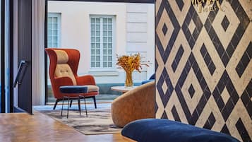 A modern hotel lobby with a red armchair, a blue sofa, and a patterned wall.