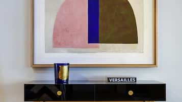 A framed abstract painting, a gold vase, and a black console table with a 'VERSAILLES' sign.
