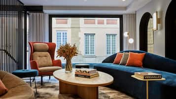 Un salon moderne comprenant un canapé, un fauteuil et une table basse, avec une vue sur un immeuble par le biais d’une grande fenêtre.