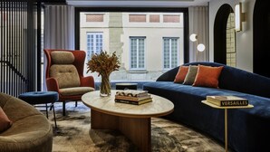 A modern living room with a sofa, armchair, coffee table, and a bookshelf. - Mercure Versailles Chateau (Versailles)