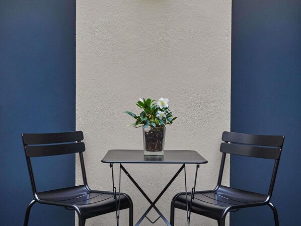 Une petite table avec deux chaises et une plante en pot placée au centre.