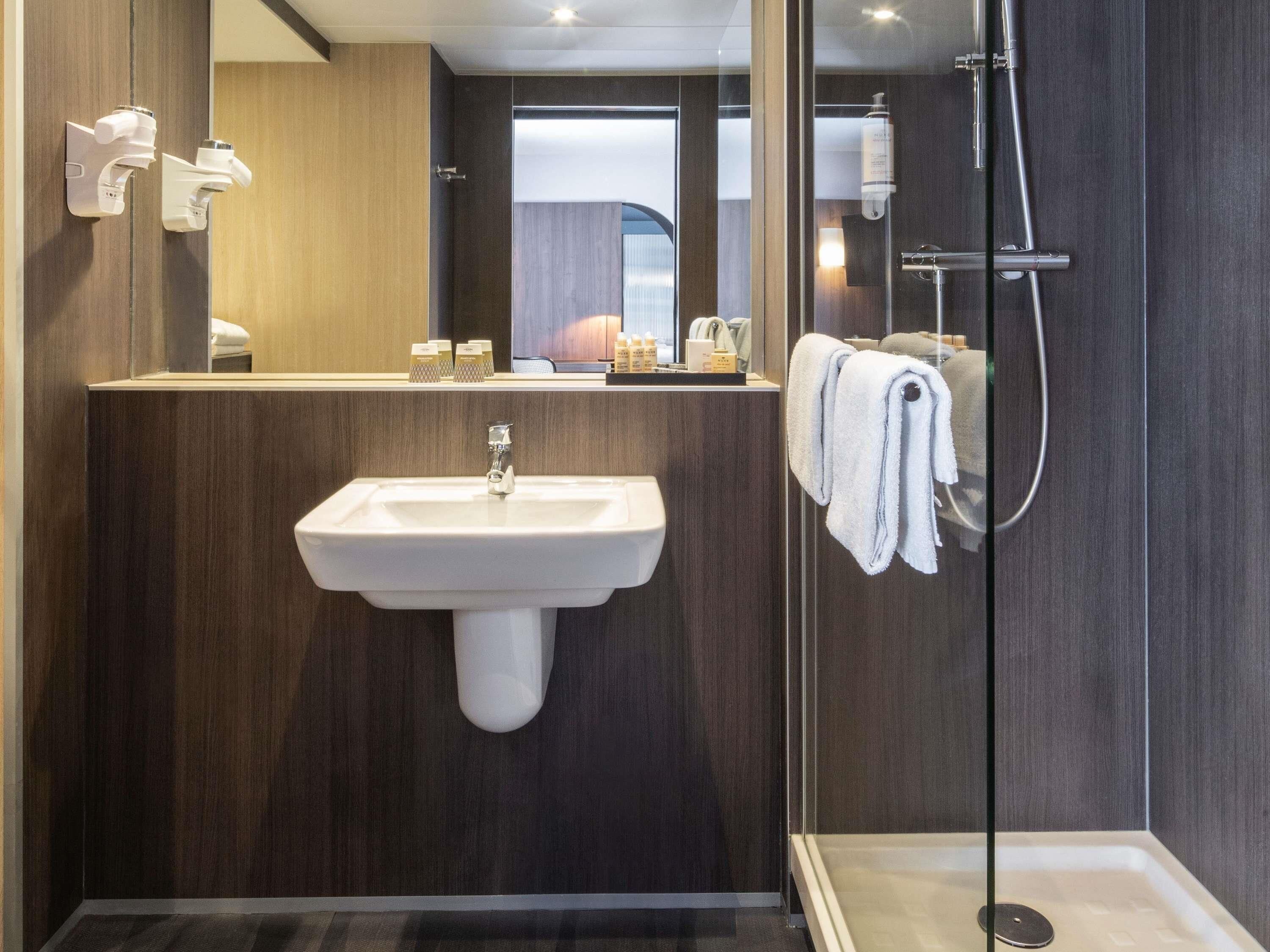 Un baño moderno con lavabo, espejo y ducha.
