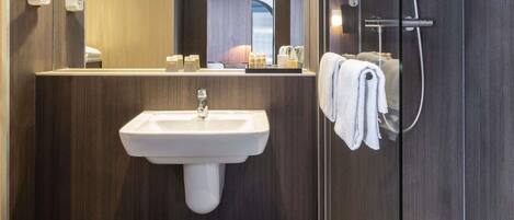 Un baño moderno con lavabo, espejo y ducha.