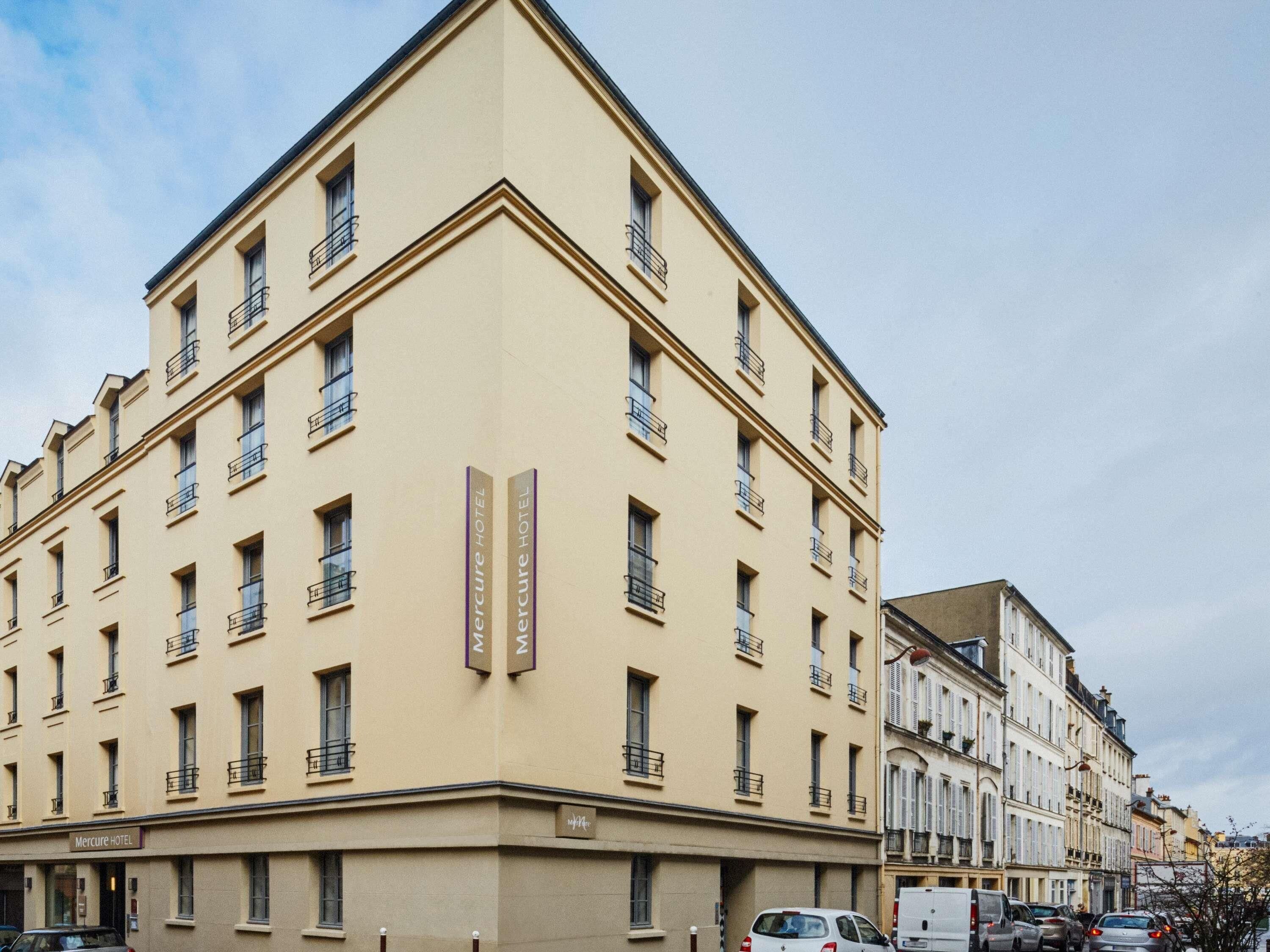 Un edificio de varios pisos con fachada plana, varios balcones y señalización que indica que es un hotel.