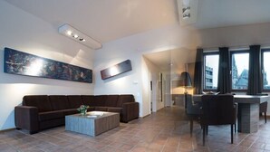 A modern living room with a brown sofa, a coffee table, and a painting on the wall. - Aquis Grana City Hotel (Aachen)
