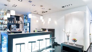 A modern bar area with a bar counter, stools, and a decorative vase. - Aquis Grana City Hotel (Aachen)