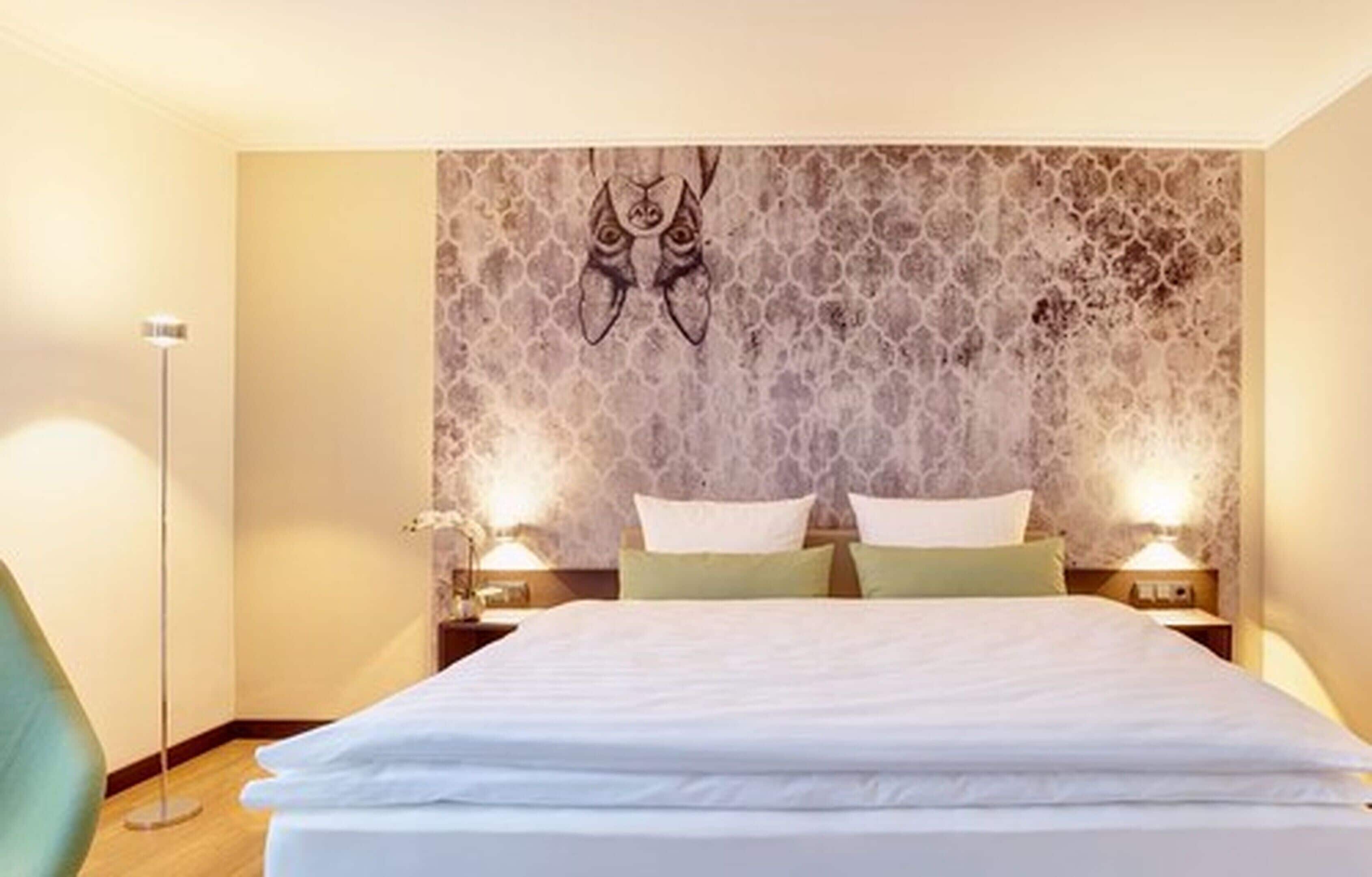 A hotel room with a large bed, two bedside lamps, and a decorative wall with a unique pattern.