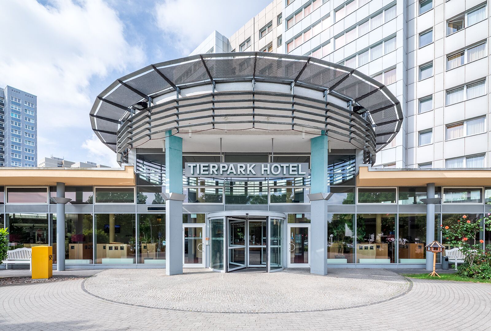 The exterior of the Tierpark Hotel with a modern entrance, glass facade, and a circular canopy structure.