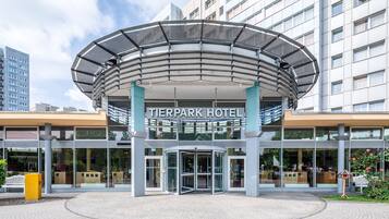 The exterior of the Tierpark Hotel with a modern entrance, glass facade, and a circular canopy structure.