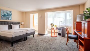 A hotel room with a bed, a desk, a chair, a television, and a window with curtains.
