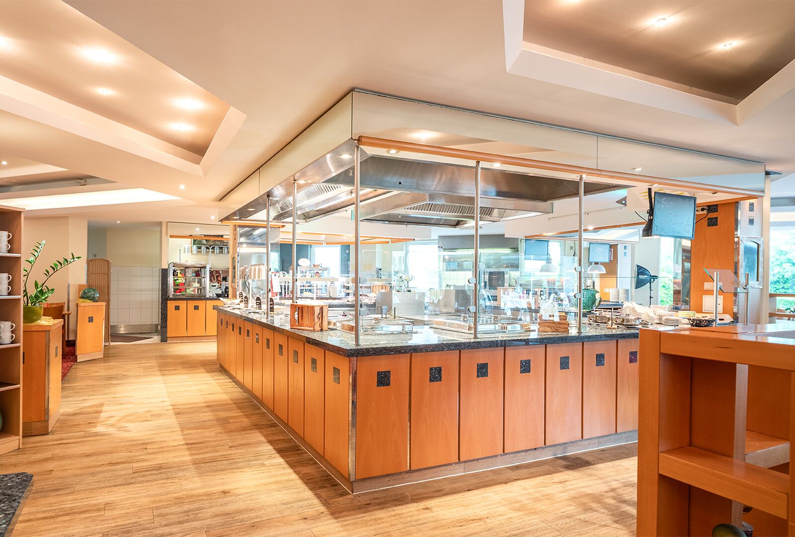 Un área de cocina moderna con armarios de madera, una vitrina de vidrio y diversos electrodomésticos.