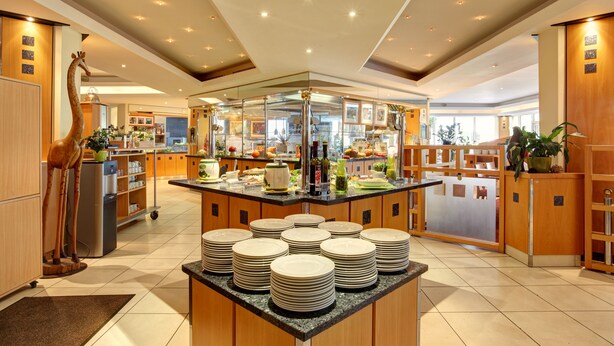 A modern kitchen with a central island, wooden cabinets, and a giraffe decoration. - Abacus Tierpark Hotel Berlin (Berlin)
