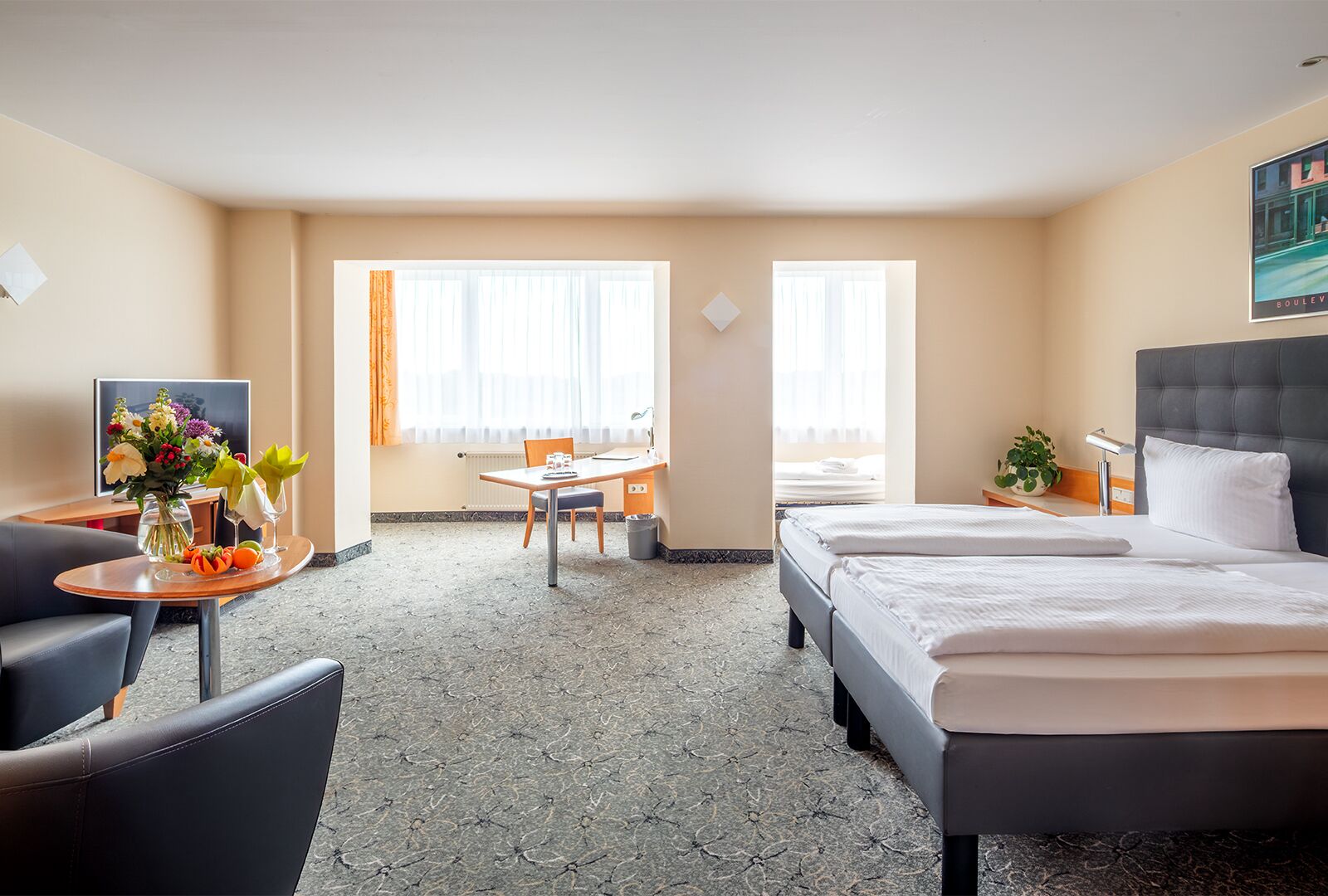 Una habitación de hotel con cama, escritorio, silla, televisor y ventana.