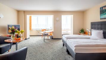 Una habitación de hotel con cama, escritorio, silla, televisor y ventana.